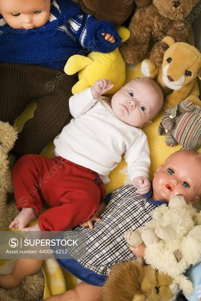 A baby in a bed with cuddly toys and dolls, Sweden.