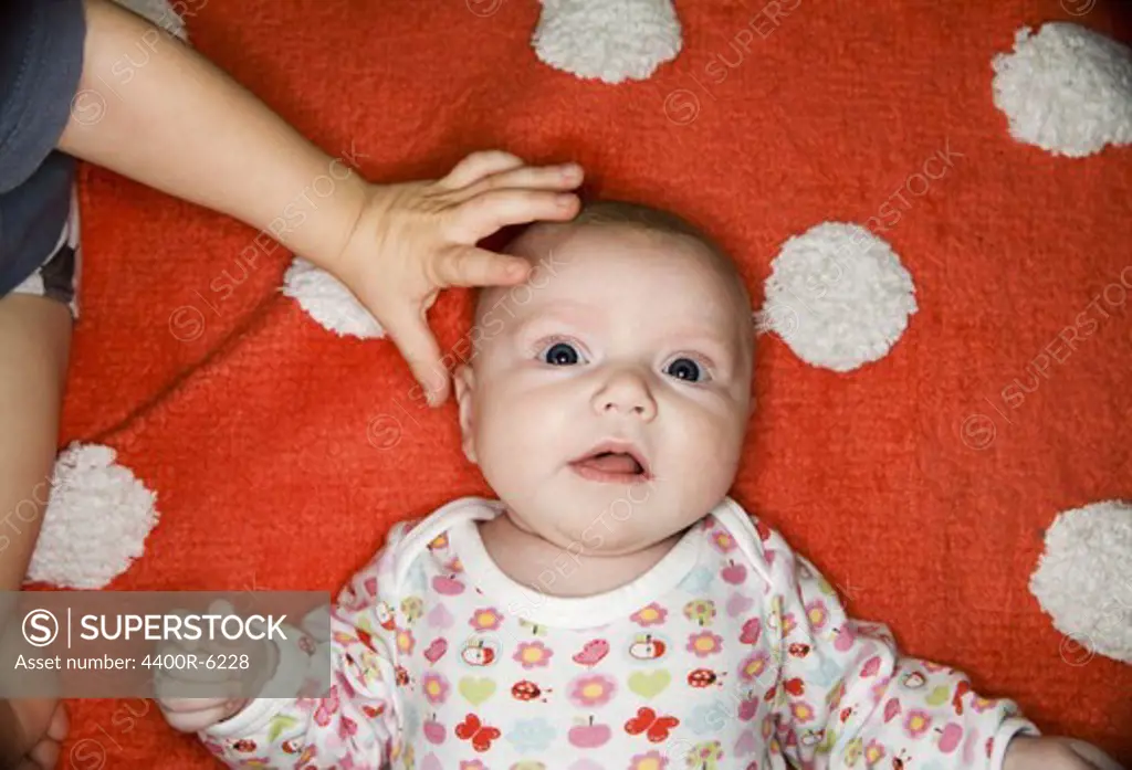 A small hand patting a baby head, Sweden.