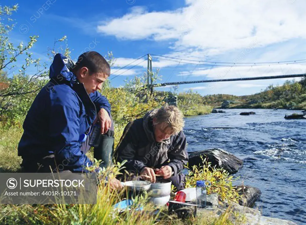 Two men preparing lunch by the riverside, Sweden.