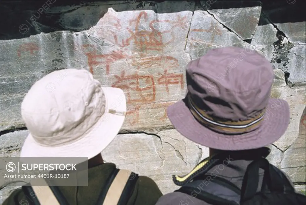 Two boys looking at rock carvings, Sweden.