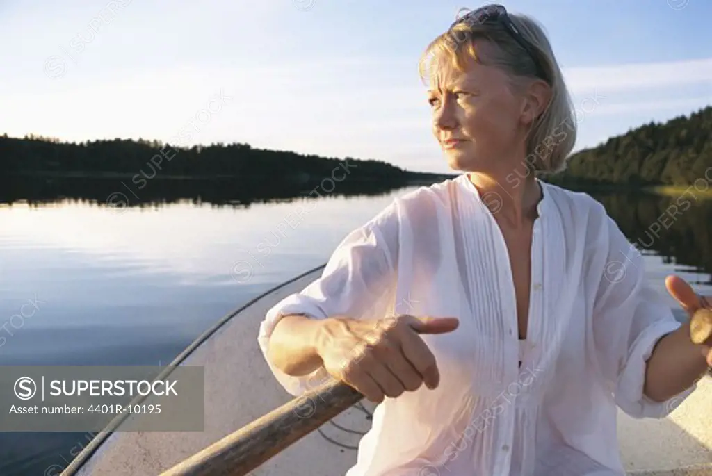 Woman rowing on a calm lake at sunset, Sweden.