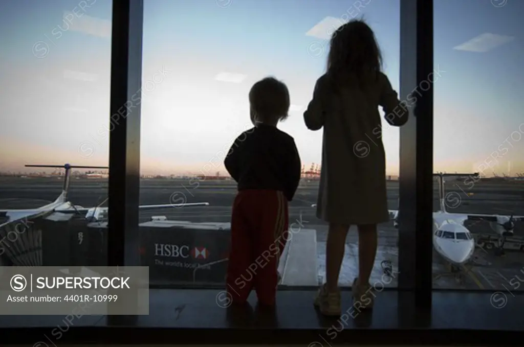 Children watching a airfield through a window