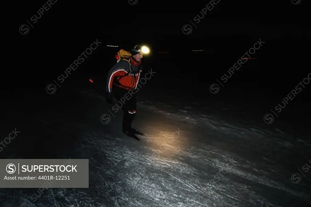 A man ice skating in the dark