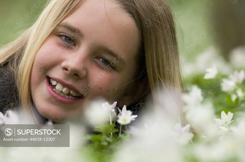 Scandinavia, Sweden, Smaland, Girl with white anemones in foreground, smiling, portrait