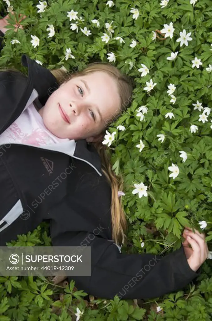 Scandinavia, Sweden, Smaland, Girl lying on white anemones, smiling, portrait