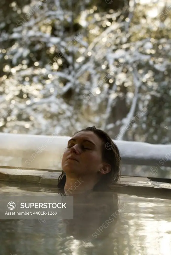 A woman having a hot bath outside in the winter, Sweden.