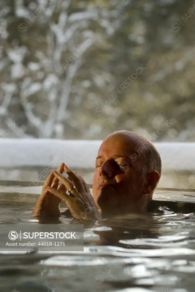 A man having a hot bath outside, a winter day, Sweden.