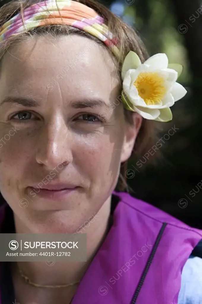 Woman wearing flower in hair, smiling, close-up, portrait
