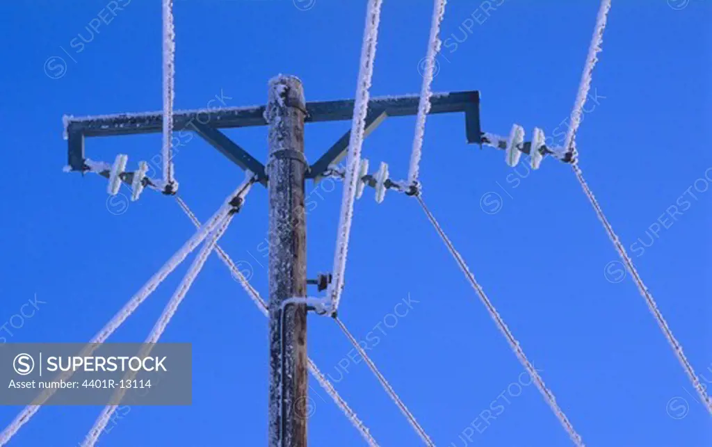 Frost on power line against blue sky