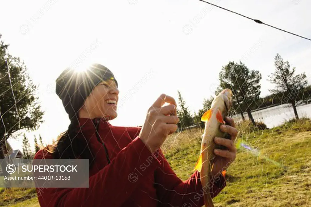 Woman taking out fish from fishing net
