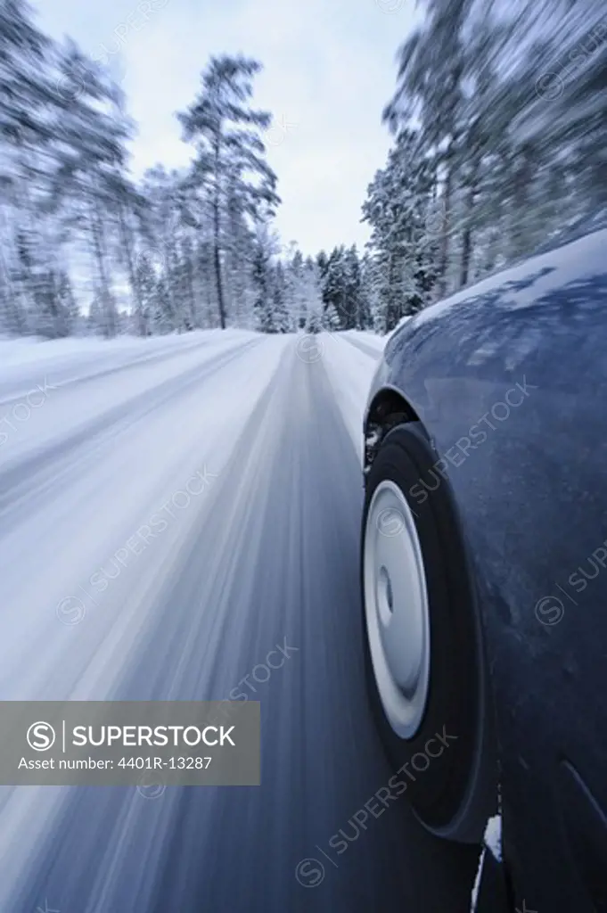 Car passing by snow covered trees