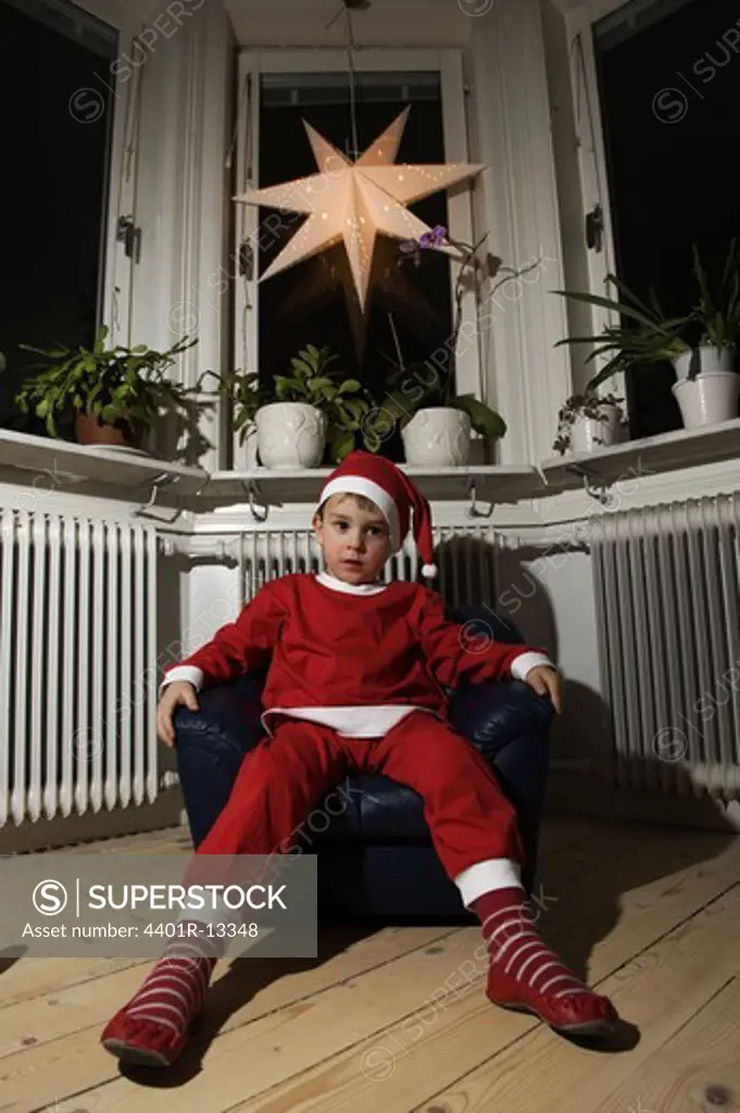 Boy wearing santa hat sitting on armchair