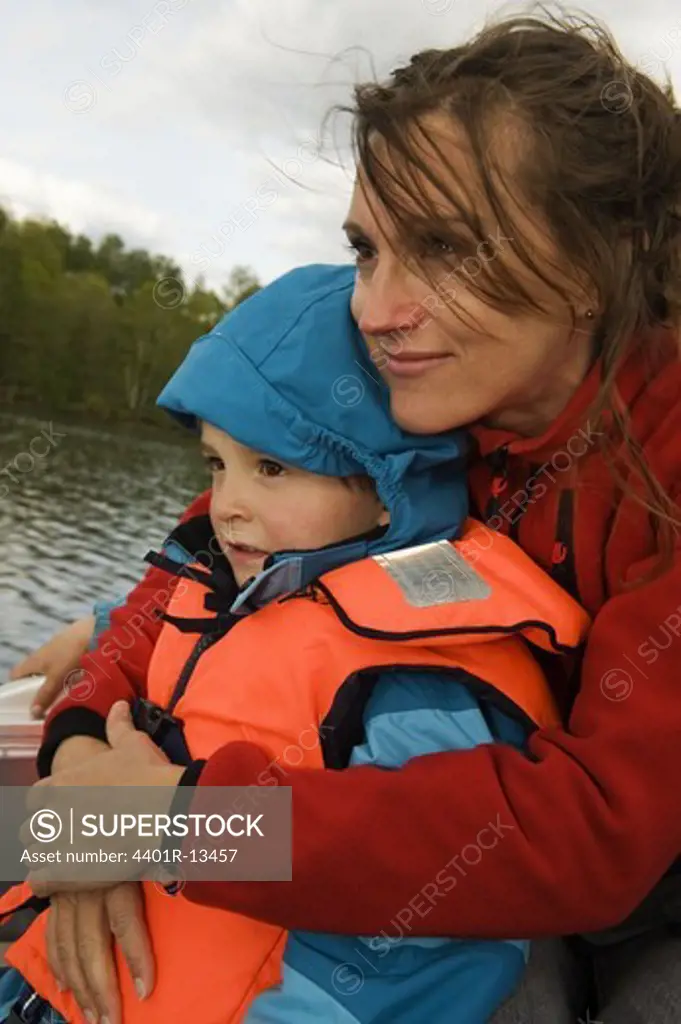 Mother and son with life jacket sitting on boat