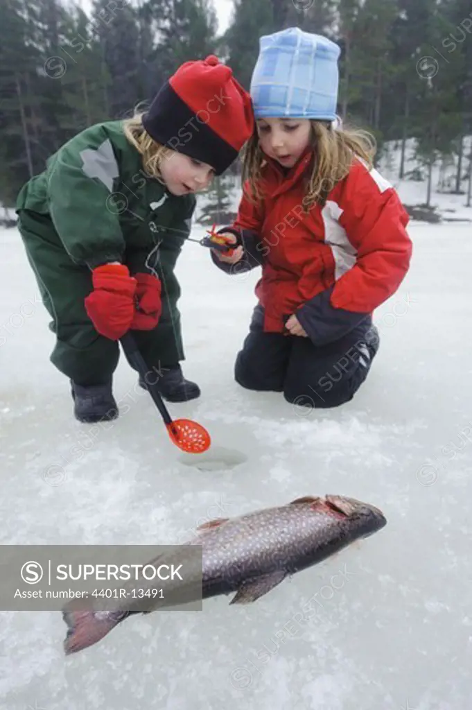 Two children fishing in snow