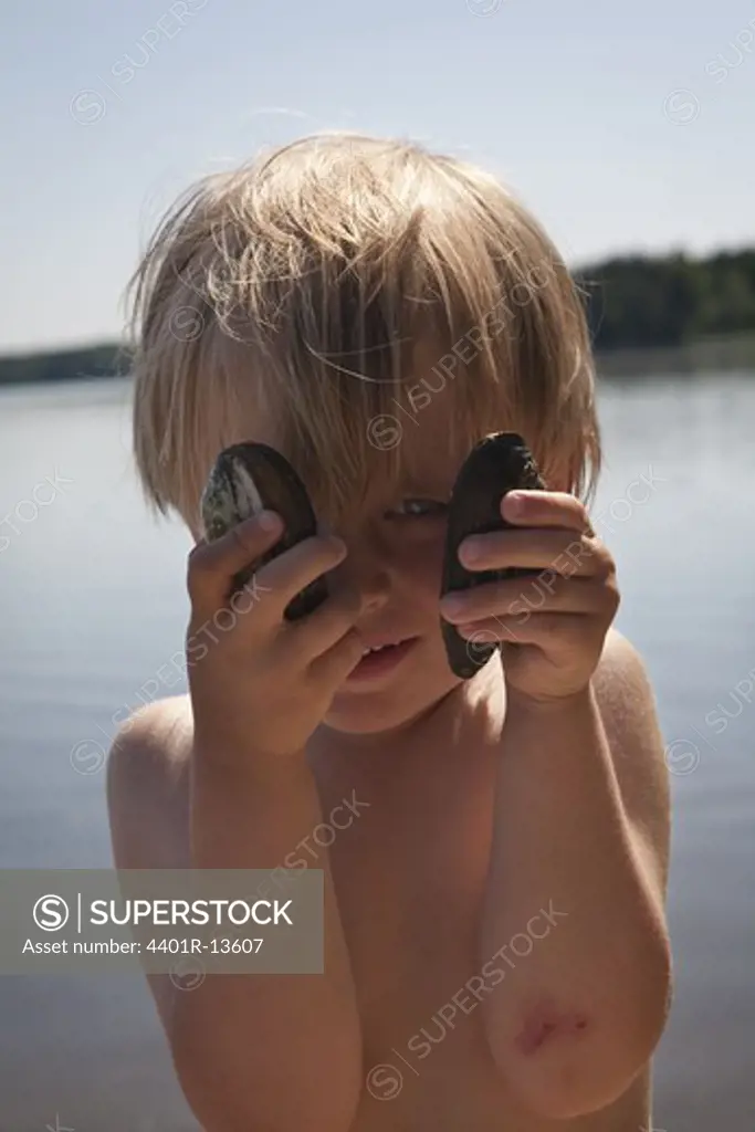 Blonde boy hiding eyes with two mussels