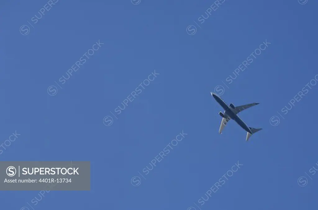 Low angle view of passenger jet flying against blue sky
