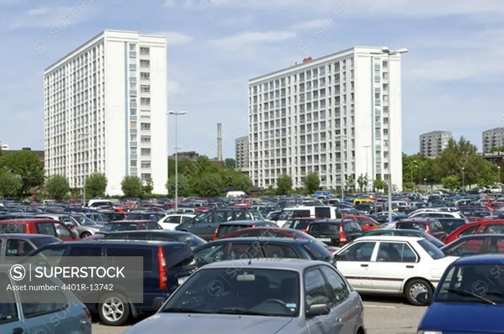 Cars on parking lot wit high rise apartment buildings in background