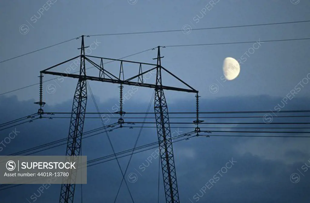 Half moon over electricity pylon