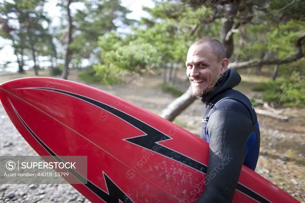 Portrait of smiling surfer carrying surfboard