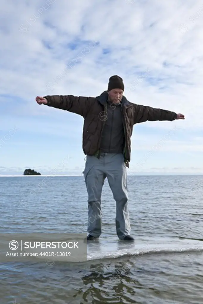 Young man standing on ice floe in sea