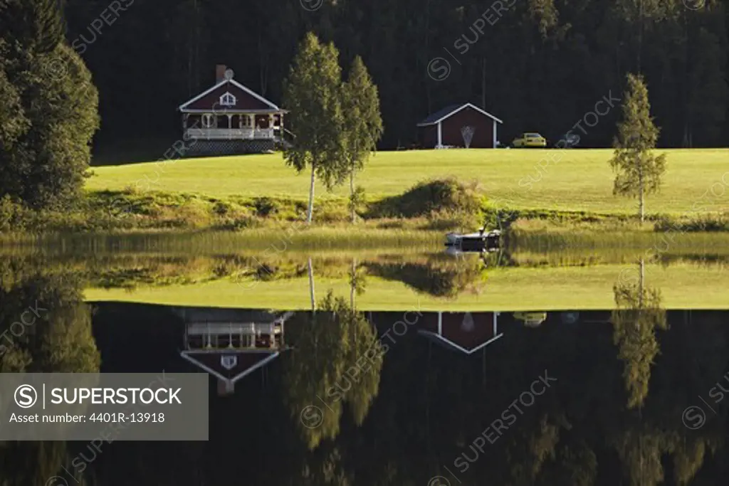 House and trees reflecting in lake