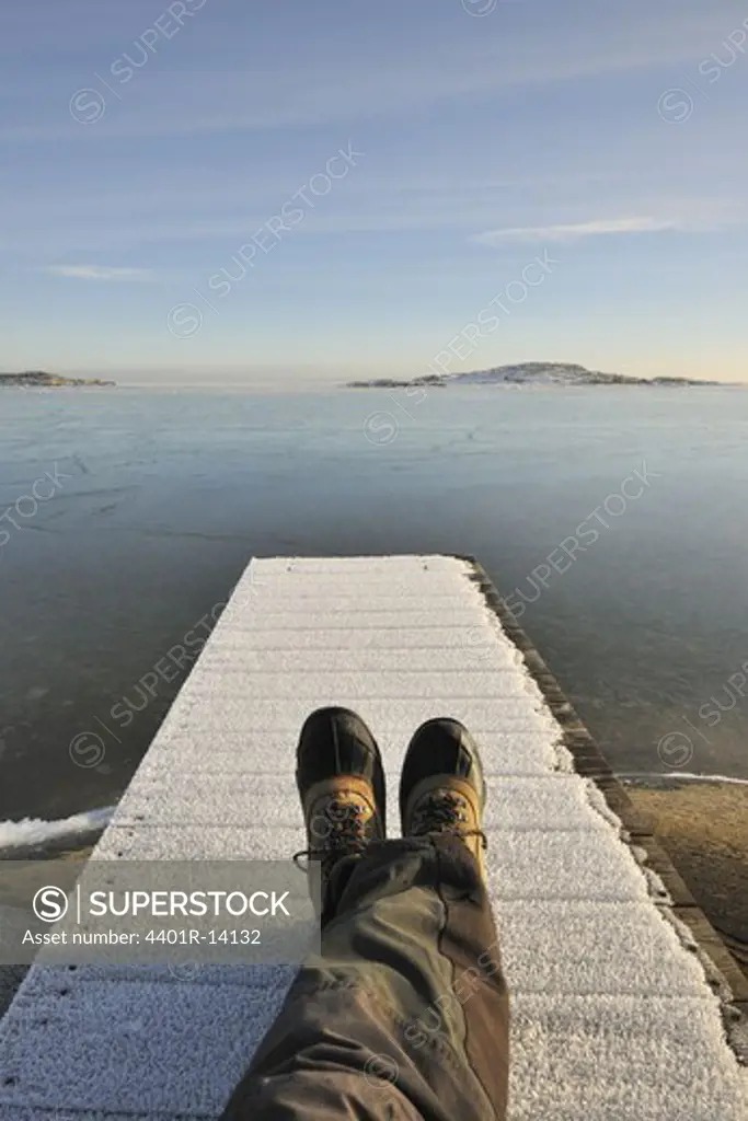 Man lying on jetty covered with frost, low section