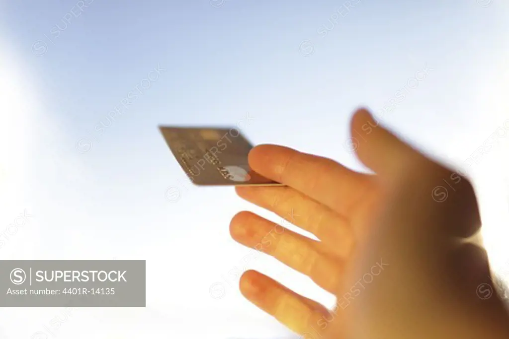 Human hand holding gold credit card, studio shot