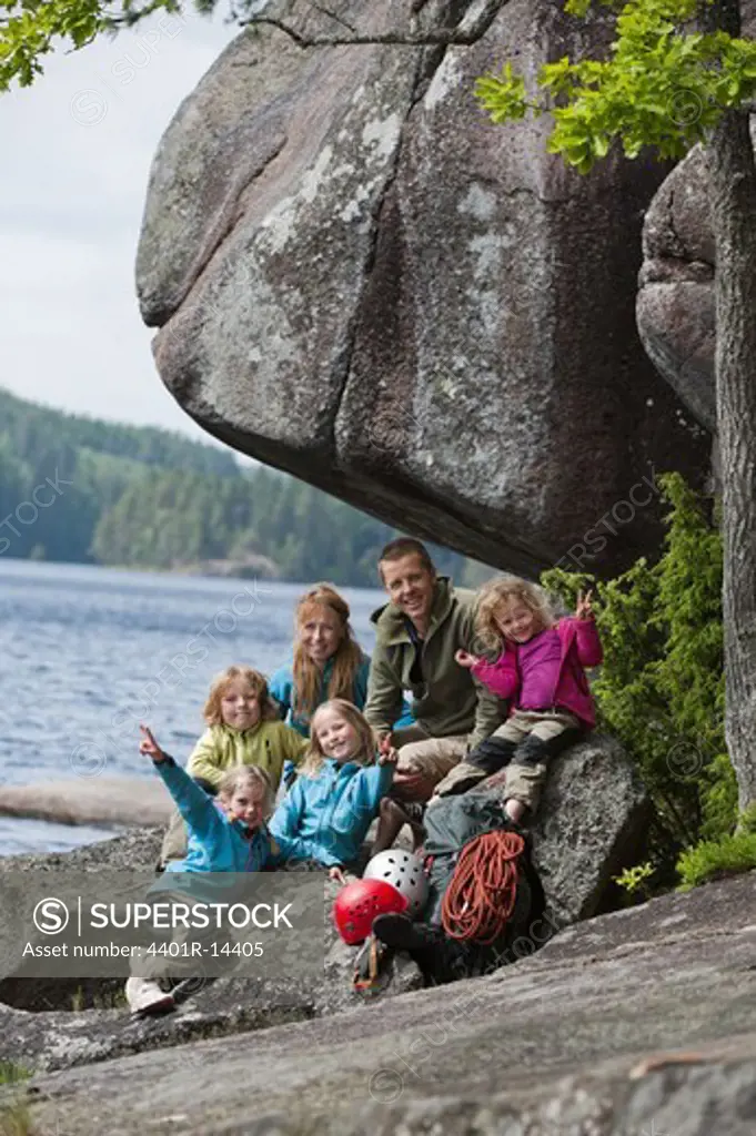 Family with four children sitting near rock with their climbing equipment