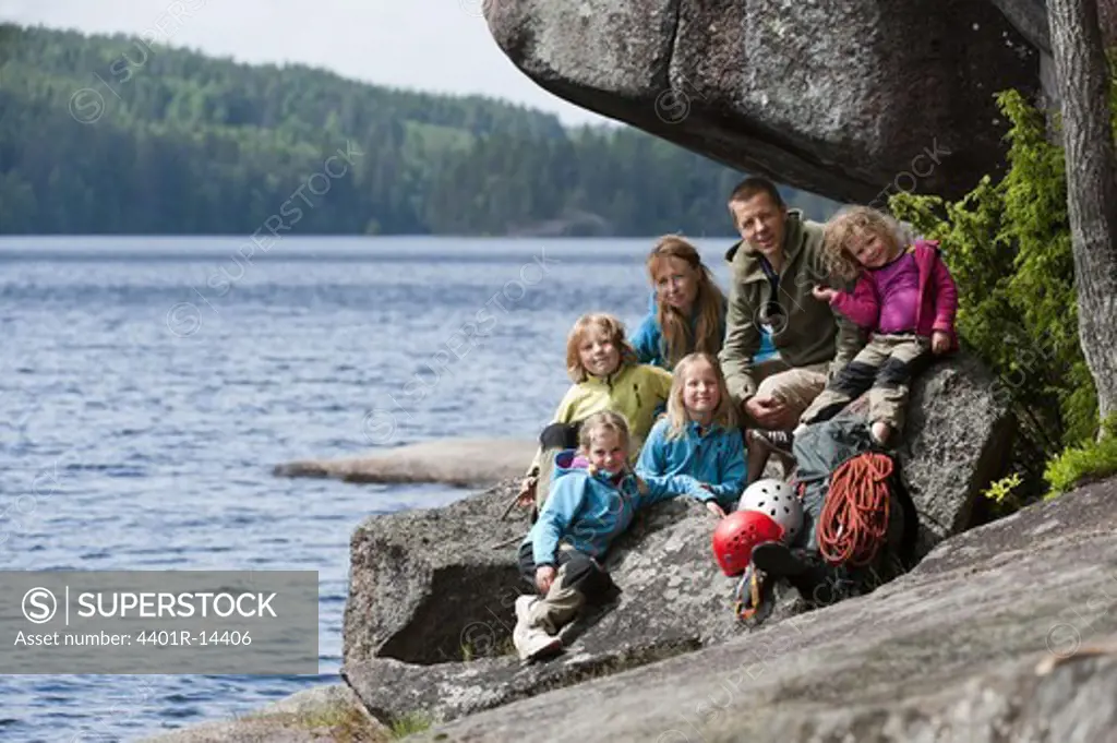 Family with four children sitting near the rock with their climbing equipment
