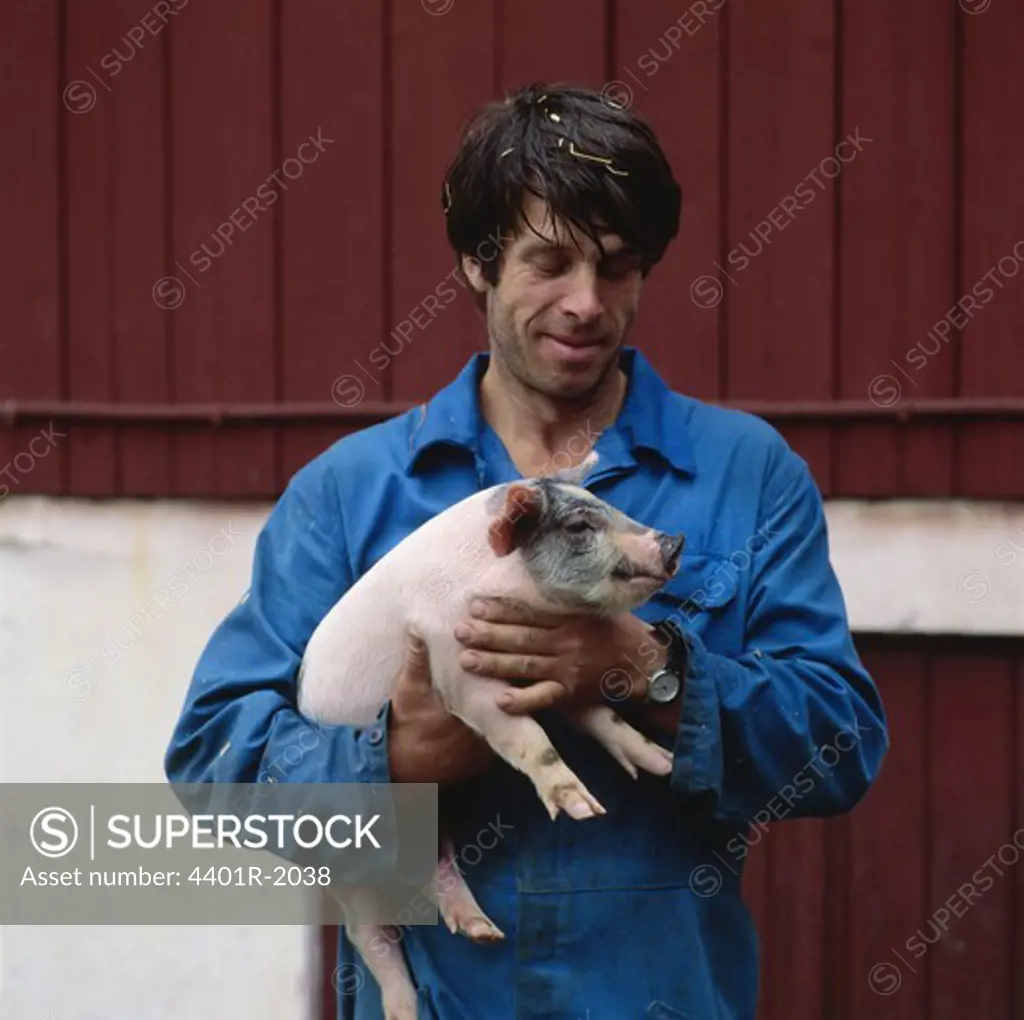 Young man holding piglet