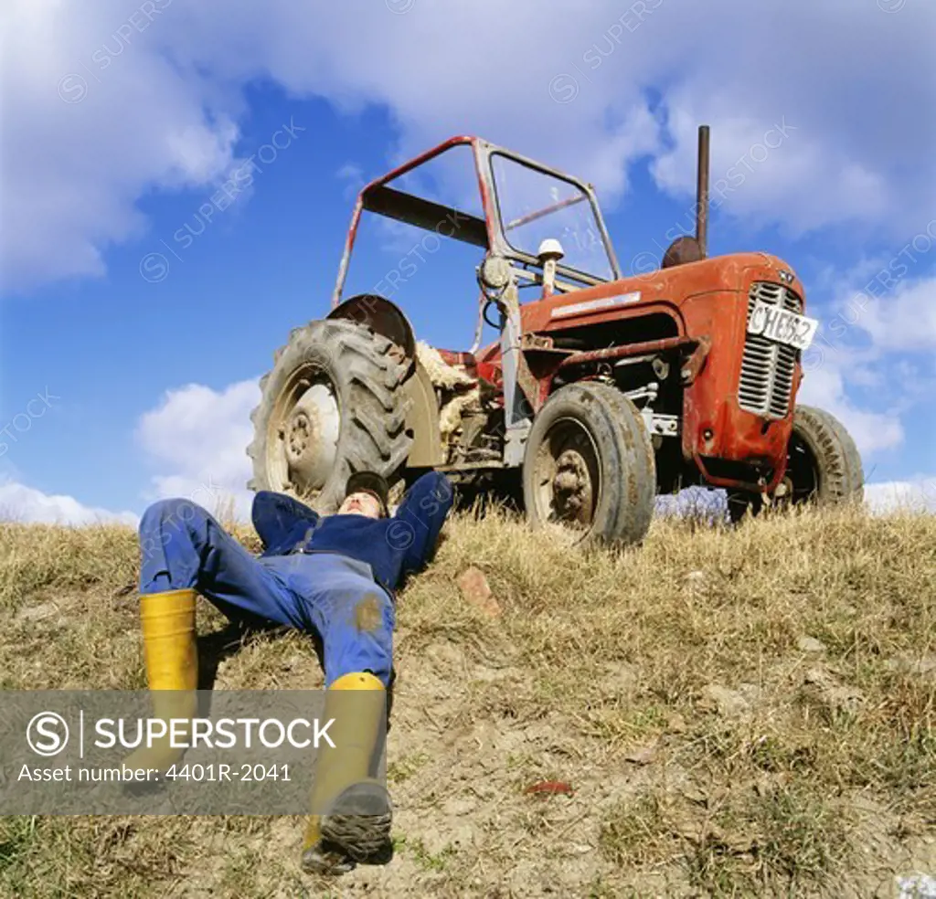 Mid adult man lying by tractor