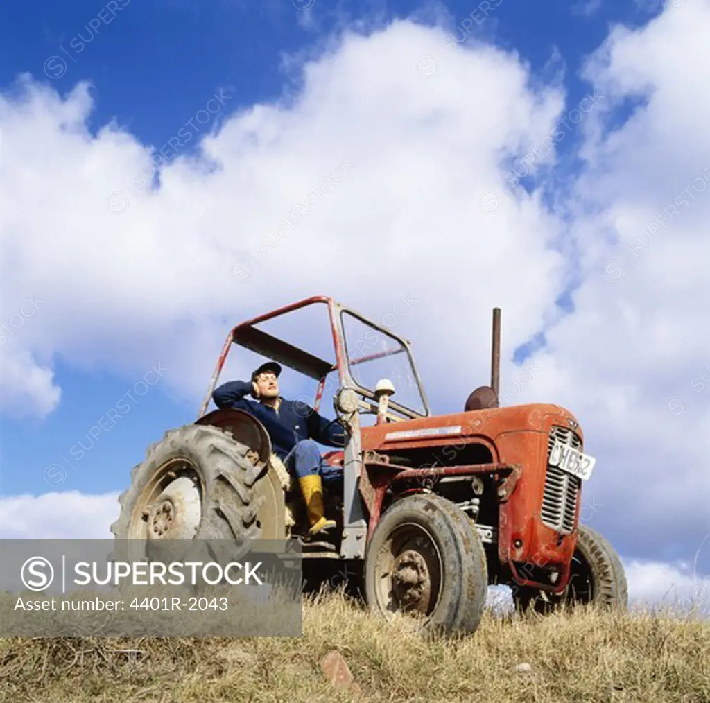 Mid adult man in tractor against sky, low angle view