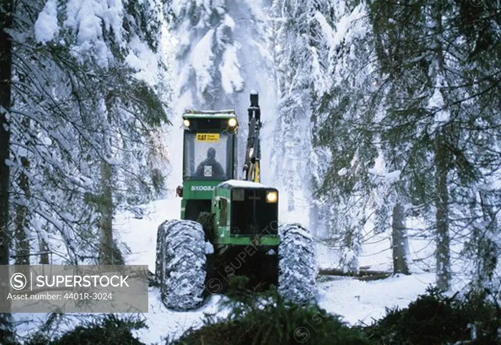 Man driving crane in snow-covered forest