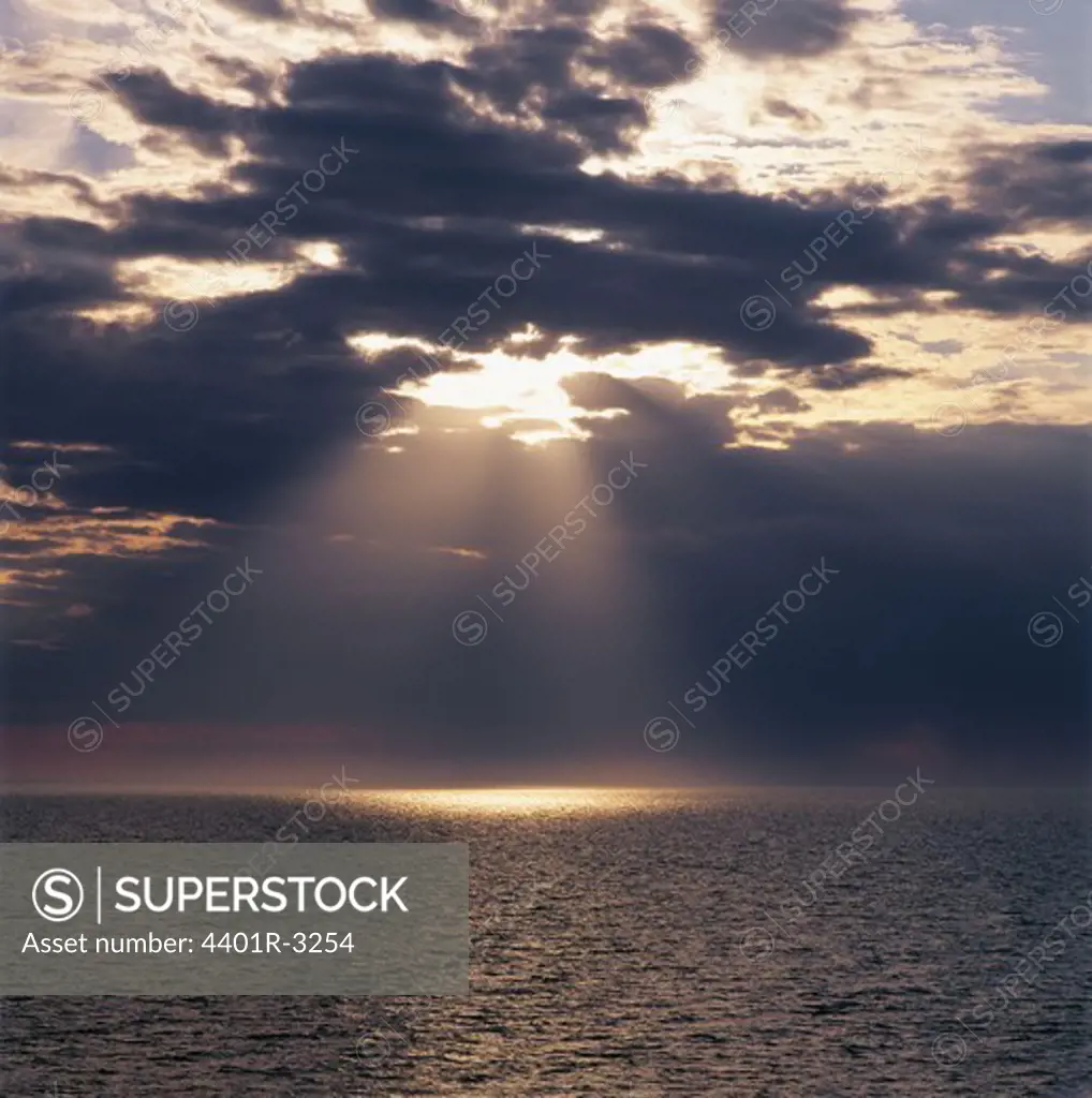 Sunrays streaming through clouds in sea