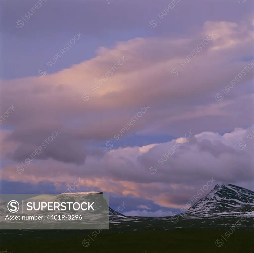 Snow-covered mountains against cloudy sky
