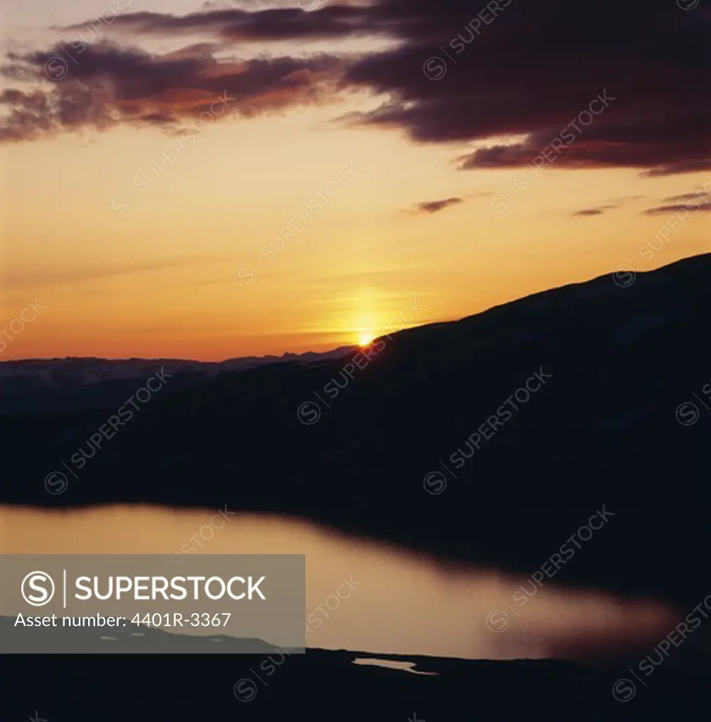 Silhouette of mountains by lake at sunset