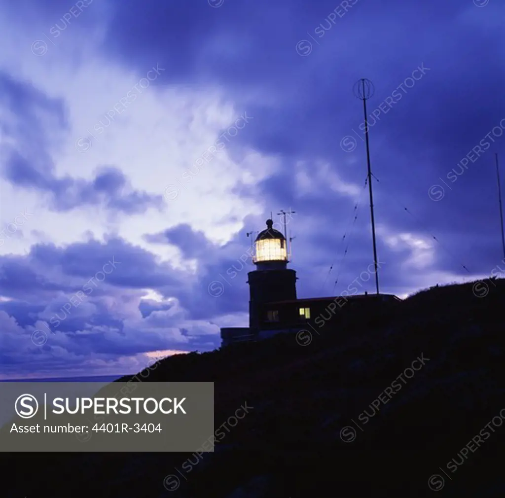 Silhouette of lighthouse on rocks against sky