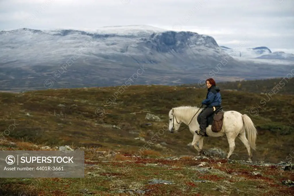 Sami woman rider on a horse in the nature, Sweden.
