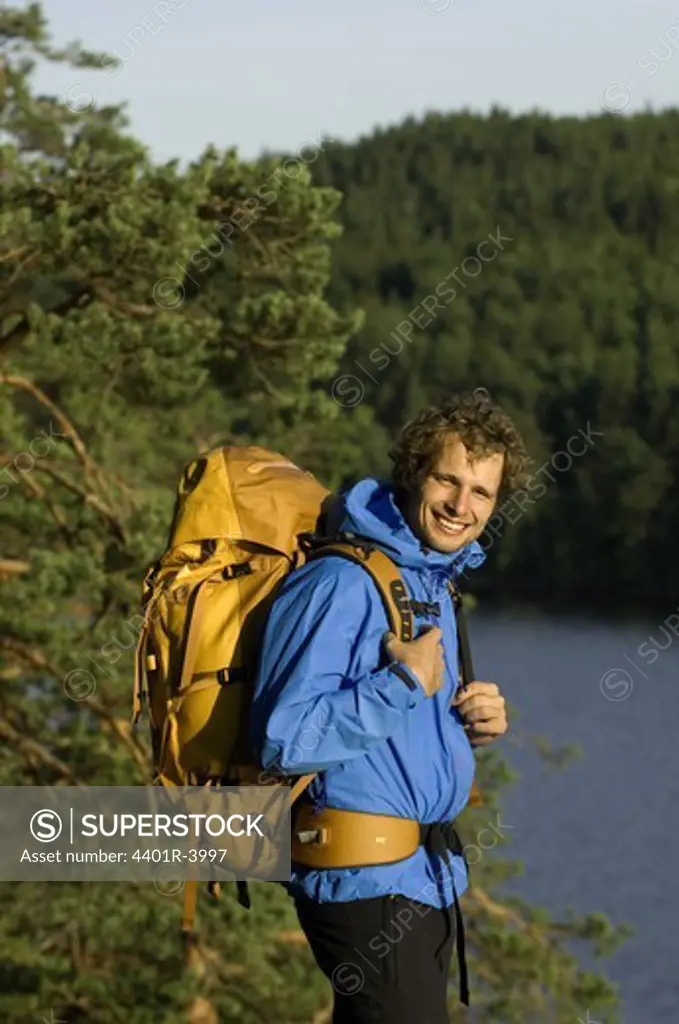 A man wearing a backpack by a lake, Sweden.