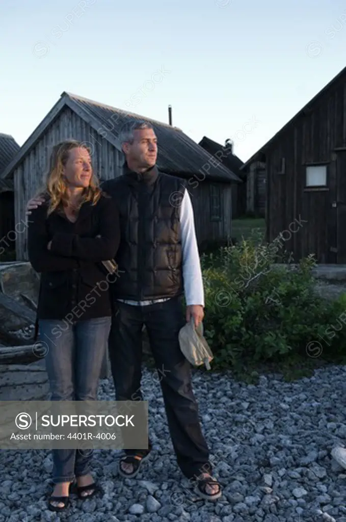 A couple standing by a fishing village, Sweden.