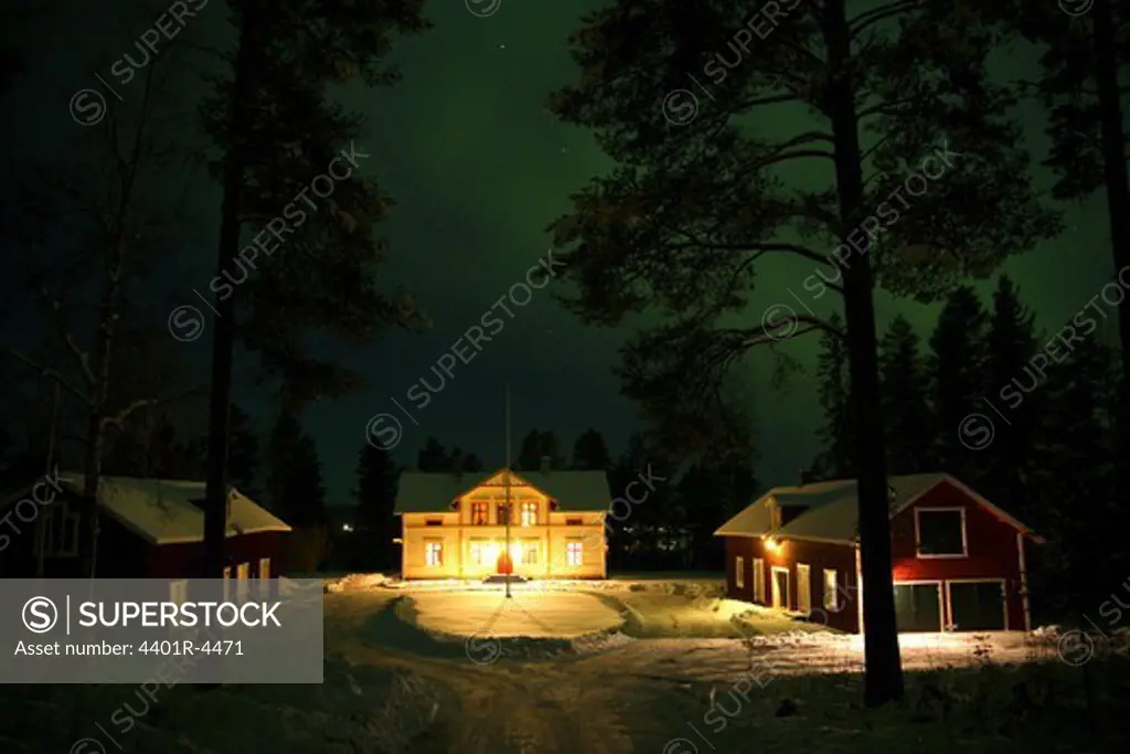 Northern lights over houses in the forest, Sweden.