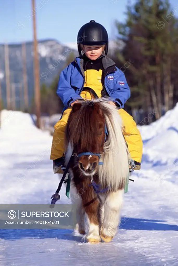 A boy on a Shetland pony a winter day, Sweden.