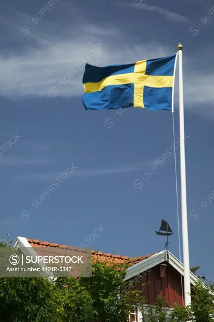 The Swedish flag outside a red cottage, Sweden.