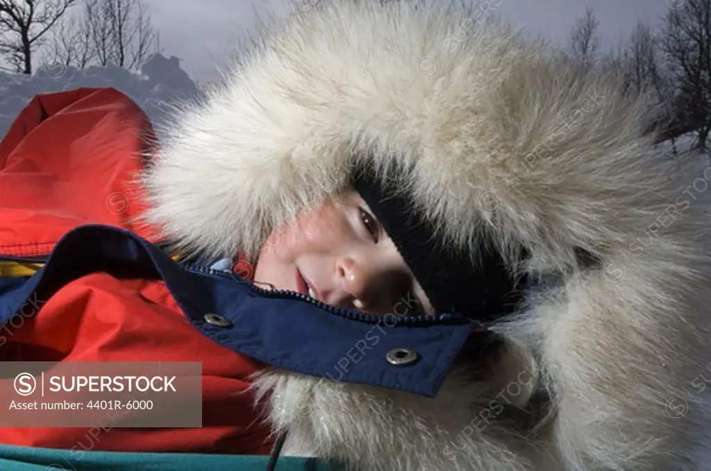 A sleeping child in a little sledge.