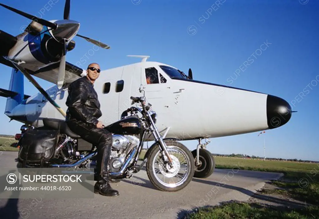 A man on a motorcycle in front of an aeroplane, Sweden.