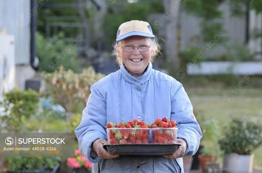 A smiling woman holding strawberries.