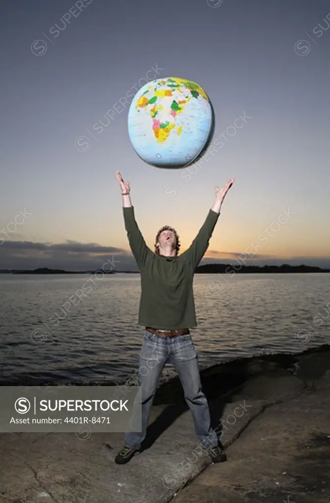 A man with a inflatable globe by the sea, Sweden.