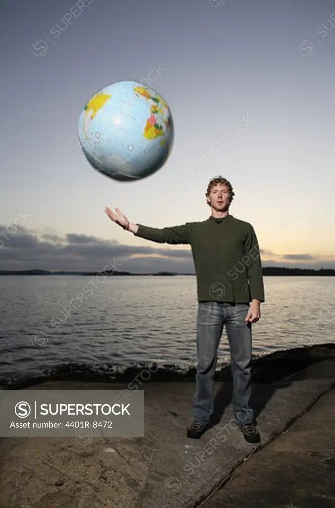 A man with a inflatable globe by the sea, Sweden.