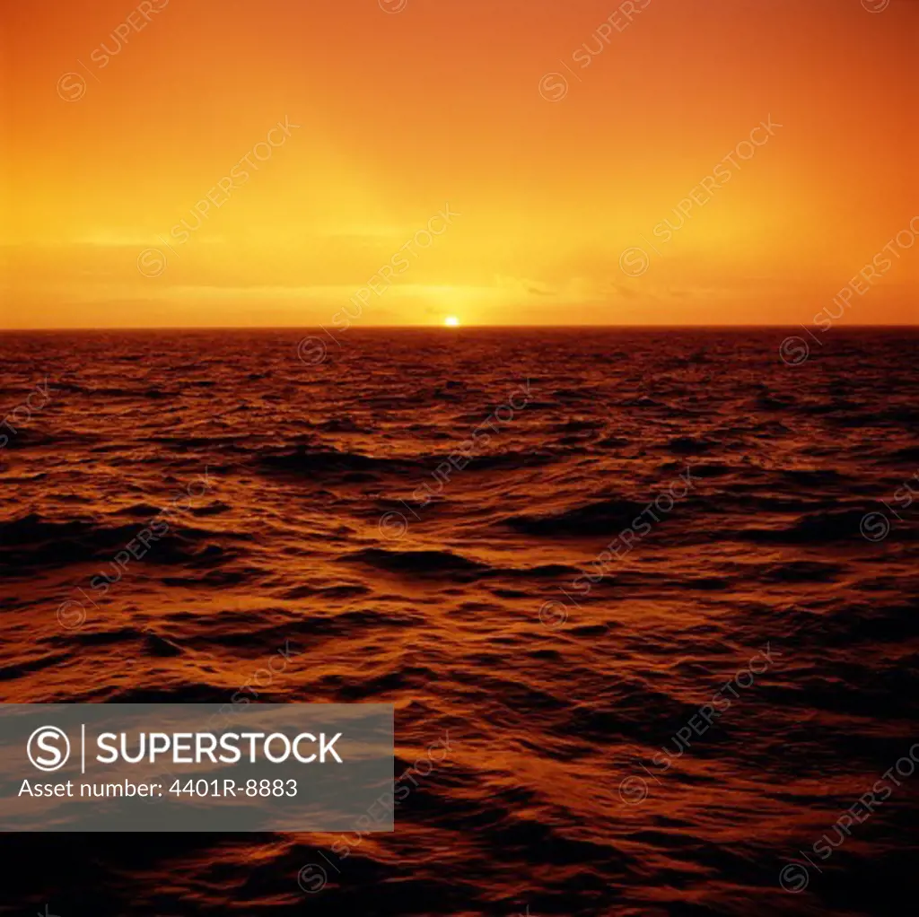 Sun setting on horizon of ocean