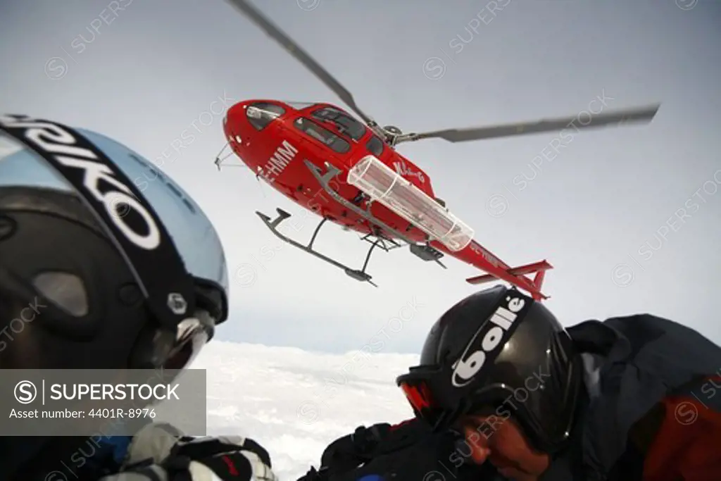 Helicopter departuring, skiers crouching down, Lapland, Sweden.